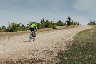 Male athlete on mountain bike riding uphill on trail