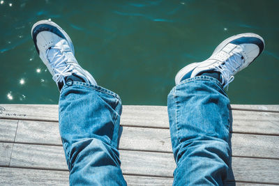 Low section of man standing against blue water