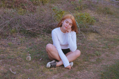 Portrait of smiling young woman sitting on land