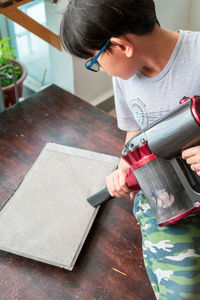 Cute boy using vacuum cleaner at home