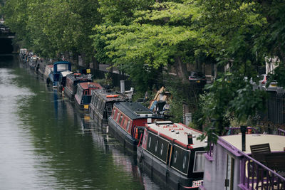 Boats moored in river by trees in city