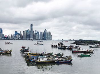 Boats moored on sea against sky in city