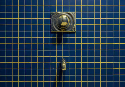 Faucet on blue tiled wall