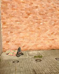 Homeless person lying on footpath by brick wall