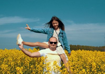 Full length of happy woman with arms raised on field against sky