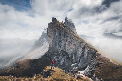 People on rocks by mountain against sky