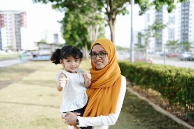 Front view of kids with her mother standing against trees