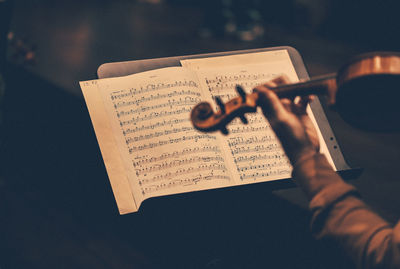 Close-up of person playing violin with musical note on table