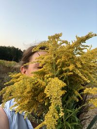 Portrait of woman by flowering plants against clear sky