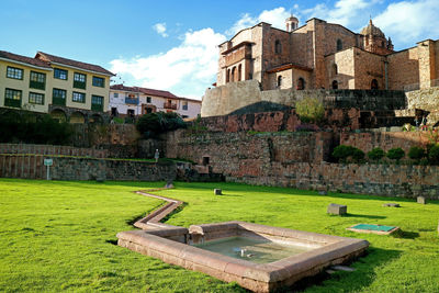 Old building by lawn against sky