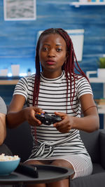 Portrait of young woman using mobile phone while sitting at restaurant