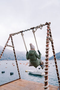 Low angle view of woman standing on rope against clear sky