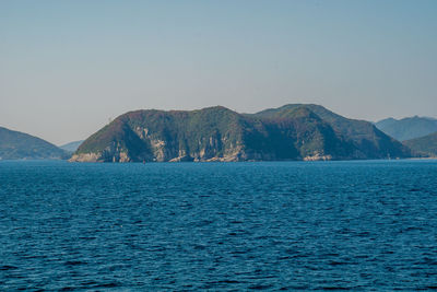 Scenic view of sea and mountains against clear sky