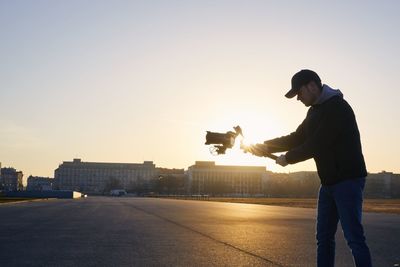 Side view of young man photographing at sunset