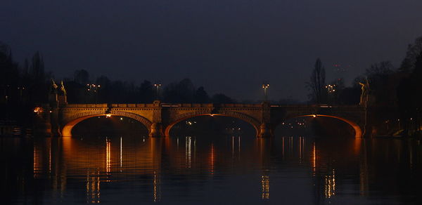 Bridge over river in city at night