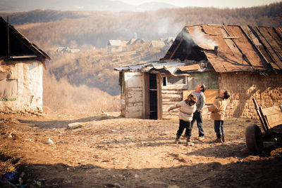 People on houses by buildings against mountain