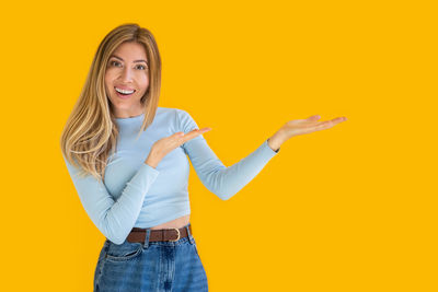 Young woman standing against yellow background