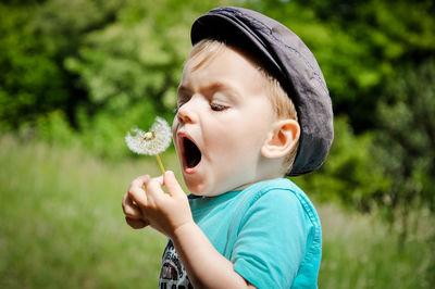 Close-up of cute boy blowing dandelion