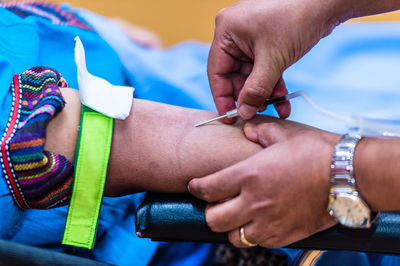 Cropped hand of male doctor injecting needle in patient hand on stretcher