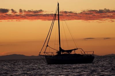 Silhouette sailboat on sea against sky during sunset