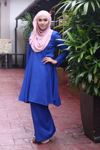 Portrait of a smiling young woman standing on footpath