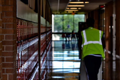 Rear view of man walking in school corridor