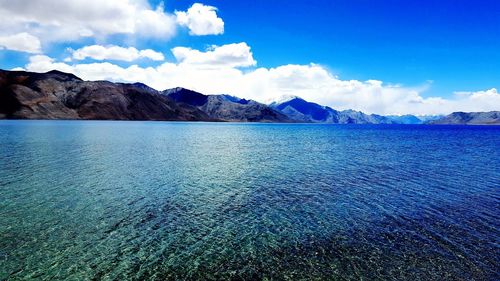 Scenic view of sea and mountains against blue sky