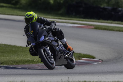 A motorcycle rider exits a turn on a racetrack on a sunny day