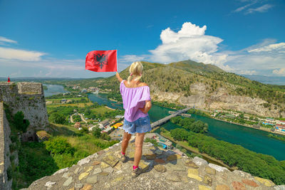 Rear view of man standing on mountain against sky