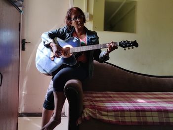 Young woman playing guitar at home