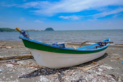 Boat moored on sea shore against sky