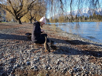 Woman feeding ducks by lake