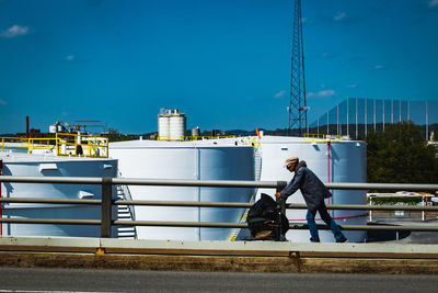 Men sitting on railing against blue sky