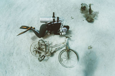 High angle view of scuba diver by abandoned bicycle in sea