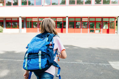 A schoolgirl girl with a school backpack on her back runs to school. 