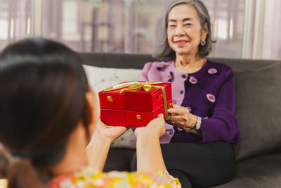 Daughter giving gift box to mother at home.