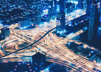 High angle view of illuminated street amidst buildings in city at night