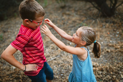 Side view of siblings playing while standing on land