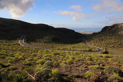 Scenic view of road by mountains against sky