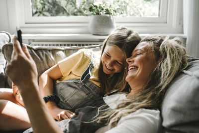 Smiling mother and daughter using digital tablet in living room