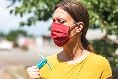 Portrait of young woman holding sunglasses