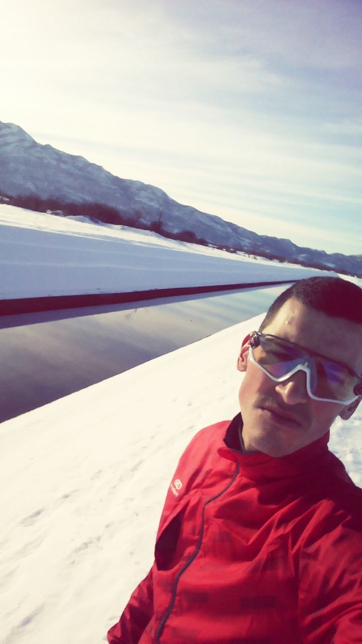 FULL LENGTH OF MAN RELAXING ON SNOW AGAINST SKY