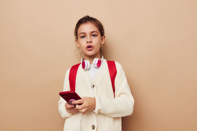 Portrait of young woman standing against pink background