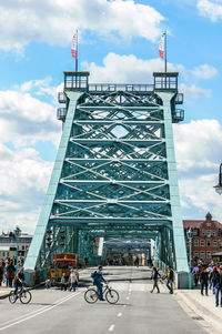 People on road against cloudy sky, blaues wunder bridge