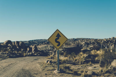 Road signs on landscape against clear blue sky