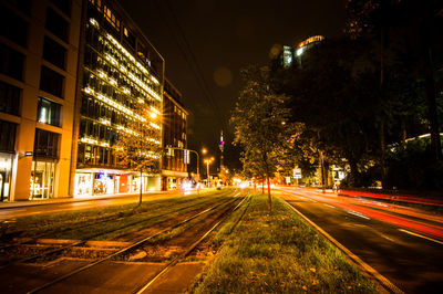 Light trails on road amidst buildings in city at night