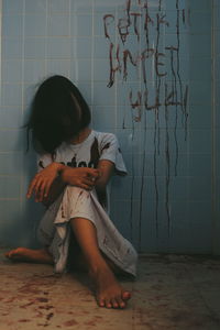 Woman with blooded text sitting against wall