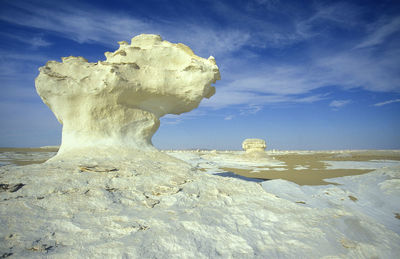 Rock formations on beach against sky