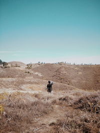 Rear view of man on field against clear sky