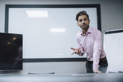 Mature businessman giving presentation in front of blank whiteboard at office